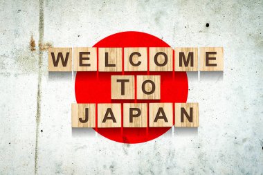 Japonya 'ya hoş geldiniz. Japonya bayrağının arka planındaki tahta bloklardaki yazıt. Seyahat et. İş dünyası.