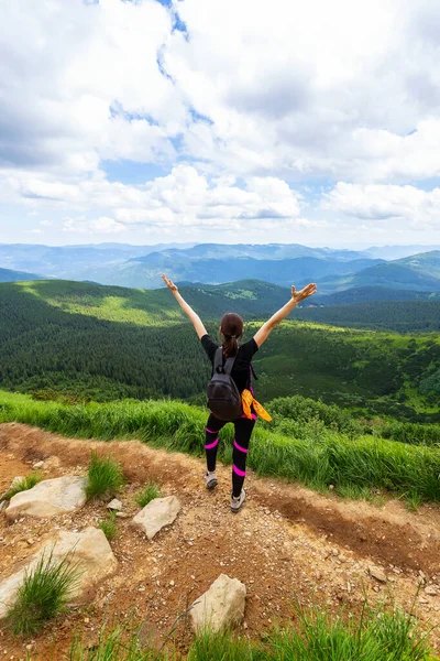 Happy young girl with raised hands on a background of beautiful mountains. Ukraine. Carpathians. Recreation. Travels.