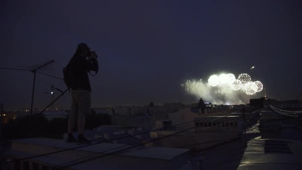 Jeune photographe debout sur le toit de l'immeuble tirant des feux d'artifice à la caméra — Video
