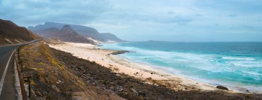 Atlantik kıyı şeridi beyaz kum tepeleri ve haddeleme okyanus dalgalarının yolda. Siyah volkan erozyon dağlar arasında yol açar. Nefes kesen sahil şeridi Calhau, Sao Vicente Island Cape Verde
