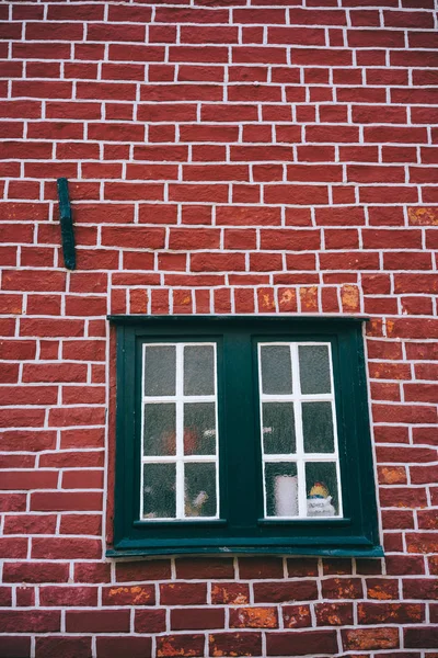 Traditional medieval German brick house in Luneburg, Germany. Fragment of the red brick facade with window frames
