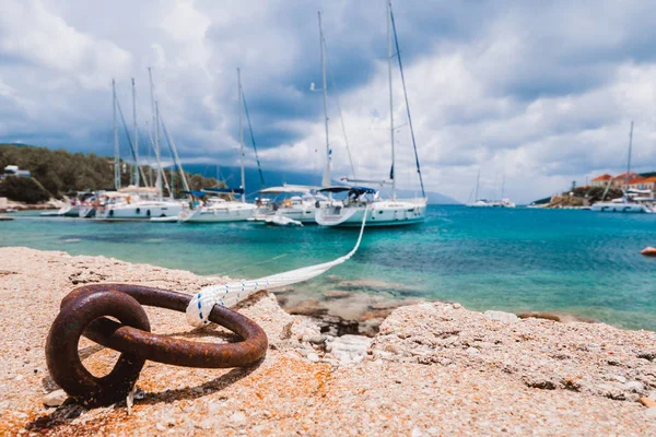 Mooring rope tied to rusty ring for rigging yachts in background. Wonderful view of port Fiskardo. Picturesque seascape of Ionian Sea. Outdoor scene of Kefalonia island, Greece, Europe