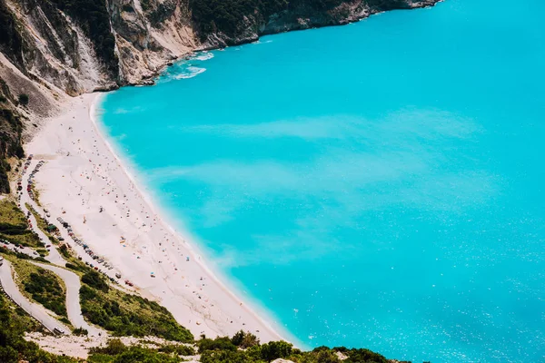 Famosa spiaggia di Myrtos con acqua blu nella giornata di sole. Turisti sulla spiaggia di sabbia, Cefalonia, Grecia — Foto Stock