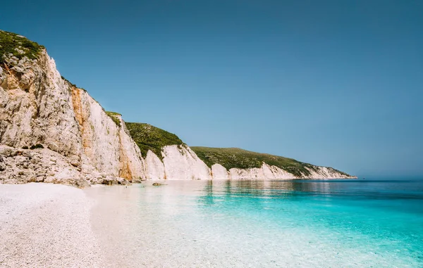 Playa Fteri en la isla de Cefalonia, Grecia. Una de las playas de guijarros vírgenes más bellas con agua de mar pura esmeralda azul rodeada de altos acantilados rocosos blancos de Cefalonia — Foto de Stock