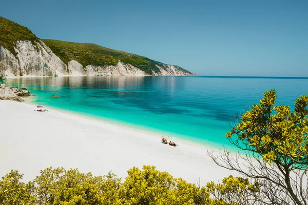 İnanılmaz Fteri beach lagün, Kefalonia Kefalonia, Yunanistan. Turistler şemsiyesi altında açık mavi zümrüt turquise deniz suyu sakin ol. Beyaz arka planda kayalar