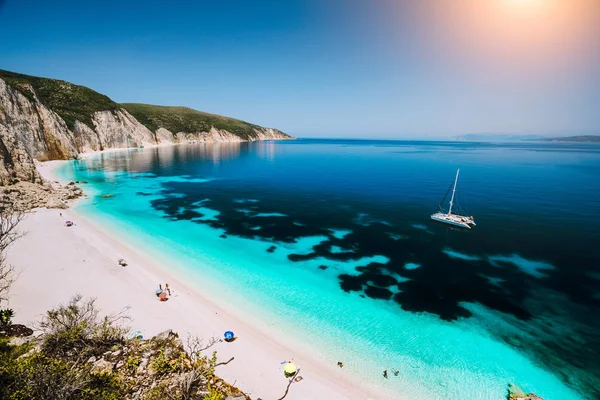 Fteri beach, Kefalonia Kefalonia, Yunanistan. Açık mavi deniz suyu beyaz Katamaran yat. Turistler gök lagün yakınındaki kum plajındaki