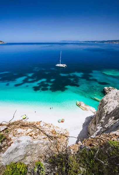 Praia de Fteri, Cephalonia Kefalonia, Grécia. Iate catamarã branco em água do mar azul claro. Turistas na praia de areia perto da lagoa azul — Fotografia de Stock