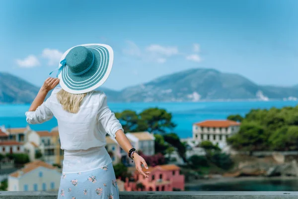 Assos sabah ışık. Mavi sunhat ve renkli sakin köy manzaranın beyaz giysiler giyen genç turist kadın. Zevk yaz gün seyahat etmek tatil Kefalonia, Yunanistan