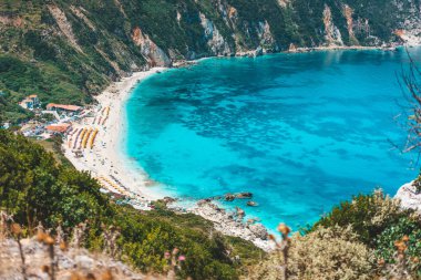 Myrtos beach with azure blue sea water in the bay. Favorite tourist destination to visit in summer on Kefalonia island, Greece, Europe clipart