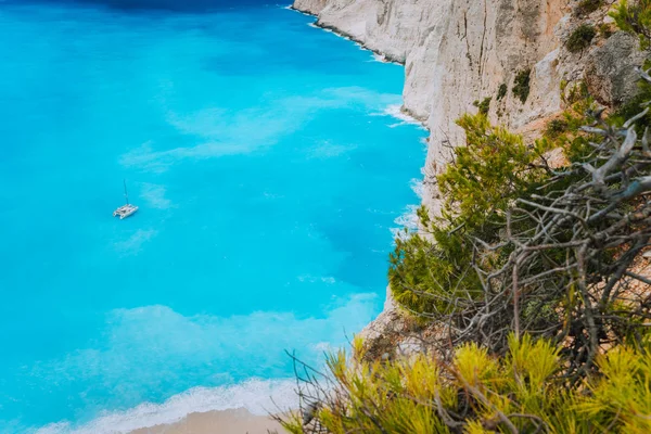 Ensam katamaran yacht i blue bay av Navagio beach. Azure turkosa havet vatten mönster nära paradise sandiga stranden. Berömda turist som besöker landmärke på ön Zakynthos, Grekland — Stockfoto