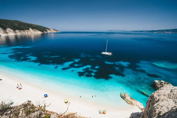 Beach leisure activity. Fteri bay, Kefalonia, Greece. White catamaran yacht in clear blue sea water. Tourists on sandy dream like beach near azure lagoon — Stock Photo, Image