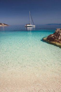 Katamaran yat tekne çapa, yelken ile güzel sakin gök mavisi lagün. Saf beyaz çakıl plajı ile deniz kayalarda
