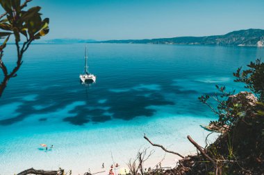 Beyaz Katamaran yat sakin mavi lagün temiz masmavi su yüzey üzerinde adlı çapa. Tanınmayan turist eğlence sahilde