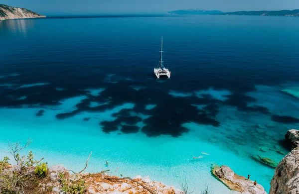 Yate catamarán blanco fondeado en la tranquila laguna de aguas azules. Los turistas irreconocibles relajarse y el ocio en la playa oculta —  Fotos de Stock