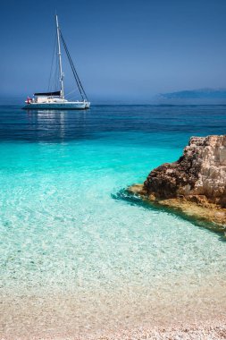 Katamaran yat tekne çapa, yelken ile güzel sakin gök mavisi lagün. Saf beyaz çakıl plajı ile deniz kayalarda
