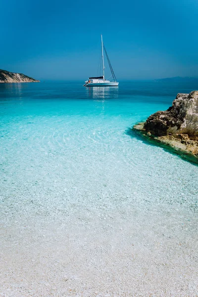 Lagune bleue azur avec voilier catamaran yacht au mouillage. Plage de galets blancs purs, quelques rochers dans la mer — Photo