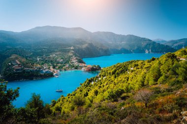 Assos köyü Kefalonia panoramik görünümü. Yunanistan. Kıyı şeridi boyunca çam ve selvi ağaçları çevrili güzel turkuaz renkli defne lagün su