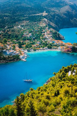 Assos köyde sabah ışık, Kefalonia. Yunanistan. Kıyı şeridi boyunca çam ve selvi ağaçları çevrili güzel turkuaz renkli defne lagün su beyaz yalnız yat