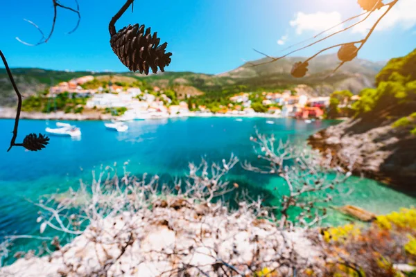 Krásná vesnice Assos, Kefalonia. Řecko. Bílá výletní jachty, pobyt na kotvě v krásné smaragdově zelené barevné laguny vody. Obklopen borovými stromy větve — Stock fotografie