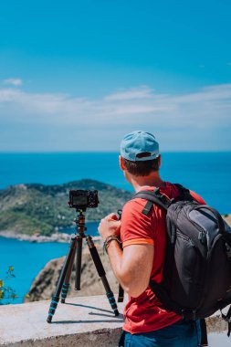 Erkek fotoğrafçı manzarayı Assos köye yakalama yansıması sırasında üstten bakış noktasından sırt çantası ile. Tripod üzerinde kamera