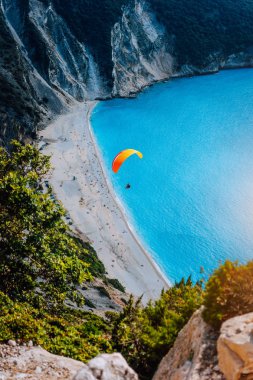 Bir mavi lagün Myrtos Beach, Kefalonia Island, Yunanistan karşı turuncu paraşüt ile bir paraşütçü skydiver figürü
