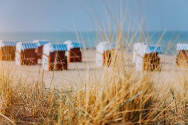 Dune çim ve mavi çatılı sandalye arka planda kum plajındaki çizgili. Travemunde Alman favori seyahat konum