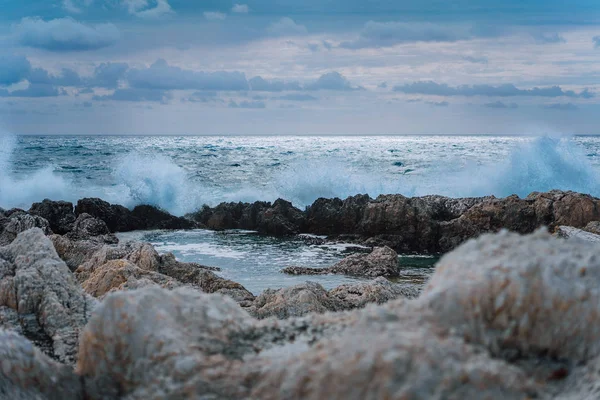 Vlny stříkající proti skalnatého pobřeží a budování přírodních koupalištích. Dramatické cloudscape — Stock fotografie