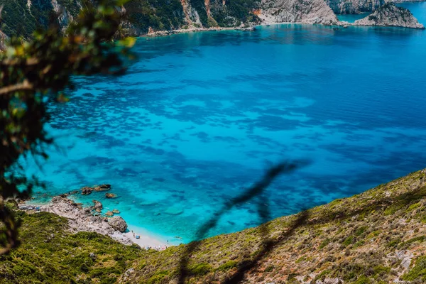 Spiaggia Myrtos con azzurro acqua di mare nella baia con motivo scuro sul fondo. Località di destinazione turistica preferita in estate sull'isola di Cefalonia, Grecia, Europa — Foto Stock