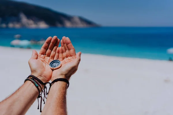 Palmeiras mão aberta segurando bússola de metal contra praia de areia e mar azul. À procura do teu conceito. Ponto de vista pontos de vista — Fotografia de Stock