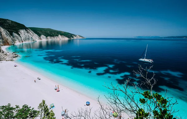 Panoramic view to remote beach wiht lonely white catamaran yacht drift in clear blue Caribbean like sea water. Tourists leisure activity on the beach with azure colored shallow lagoon — Stock Photo, Image