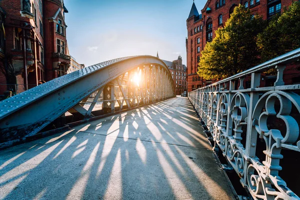 Ponte no antigo bairro de armazém Speicherstadt de Hamburgo com luz do pôr do sol à noite. Sombras longas em tempo de hora de ouro — Fotografia de Stock