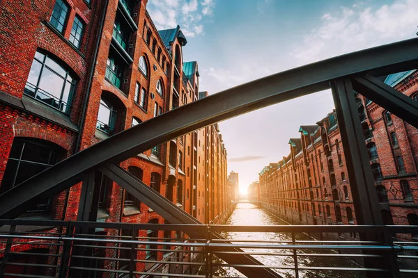 Kırmızı tuğla ambar - Hamburg Almanya, bölgede Speicherstadt sıcak gün batımı ışıkla dolu kanal bakış açısı ile çelik köprü kemer kiriş tarafından çerçeveli — Stok fotoğraf
