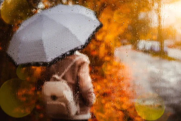 Прекрасний золотий осінній сезон. Акварель, як розмита блондинка з рюкзаком і яскравою парасолькою, стоїть під дощовими краплями і краплями. На екрані спалахує сонячний промінь. Мокра погода — стокове фото