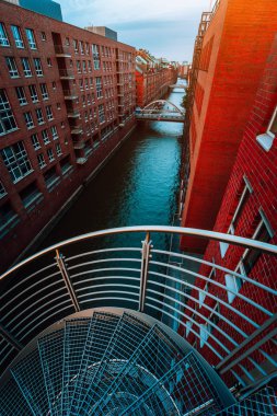 Eski depo bölgesinde kanal tarafında kırmızı tuğla binaların Speicherstadt Hamburg ile spiral merdivenler. Mavi saat
