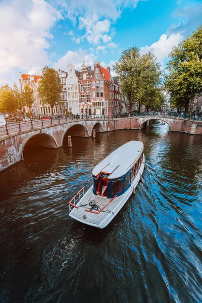 Tour boot aan beroemde Nederlandse gracht op een zonnige dag, traditionele Nederlandse bruggen, middeleeuwse huizen. Amsterdam-Holland — Stockfoto
