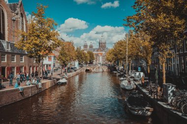 Amsterdam, Hollanda - 09 Eylül 2018: Kanal ve St. Nicolas Church Amsterdam, Hollanda bir sonbahar günü içinde. Kanalı'nın kıyısında turist rahatlatıcı. Avrupa'nın tatil