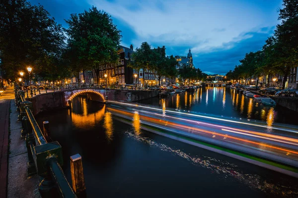 Overnachting in Amsterdam. Licht routes en verlichte bruggen over het kanaal van de stad in schemerlicht. Holland, Nederland. Lange blootstelling — Stockfoto