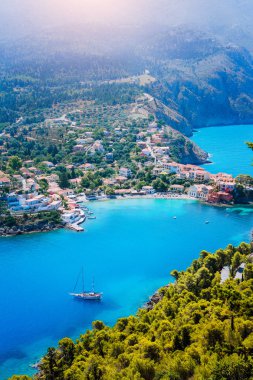 Assos köyde sabah ışık, Kefalonia. Yunanistan. Kıyı şeridi boyunca çam ve selvi ağaçları çevrili güzel turkuaz renkli defne lagün su beyaz yalnız yat.
