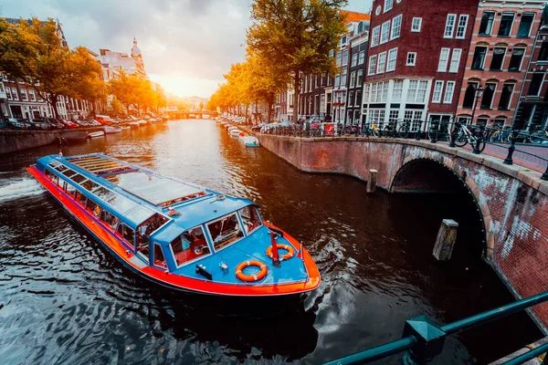 Tour boot aan beroemde Nederlandse gracht op zonsondergang avond. Traditionele Nederlandse bruggen en middeleeuwse huizen. Amsterdam-Holland — Stockfoto