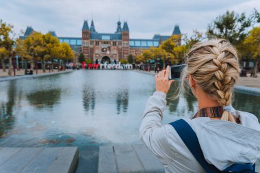 Kadın turist alarak fotoğraf Rijksmuseum Amsterdam'ın cep telefonu. Europe şehir gezisi kavramında seyahat