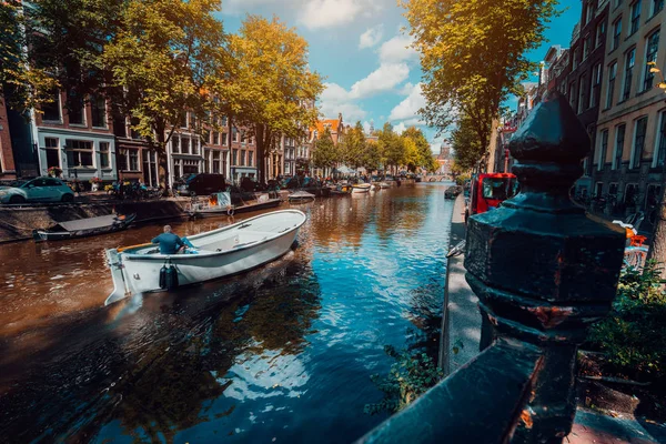 Kanal in Amsterdam in der Herbstsonne. Boot schwimmenden von Bäumen gesäumten Kanal, lebendige Reflexionen, weiße Wolken am Himmel. Niederlande beherbergt Wahrzeichen der Landschaft — Stockfoto