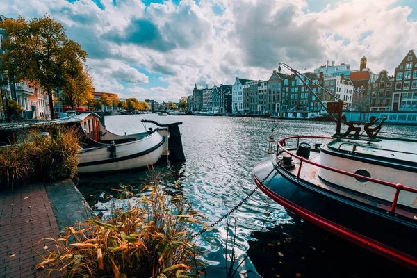 Amsterdam canal Singel con casas holandesas típicas y casas flotantes durante el soleado día de otoño. Árboles dorados y un paisaje nublado increíble. Holanda, Países Bajos — Foto de Stock