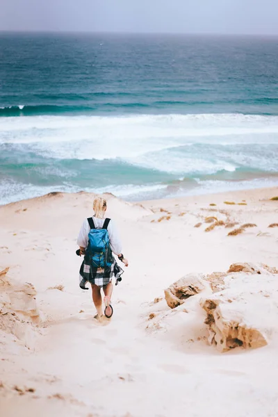 여자는 모래 언덕을 내려가는 가방을 들고 외로운 해변을 향해 걸어 갑니다. 사 오 비센테 카보베르데 — 스톡 사진