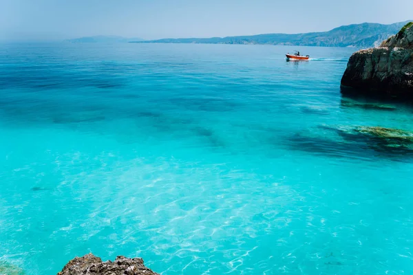 Kleines rotes Boot, das auf klarem, blauem Meerwasser schwimmt. Sommer Strandurlaub Entspannungskonzept — Stockfoto