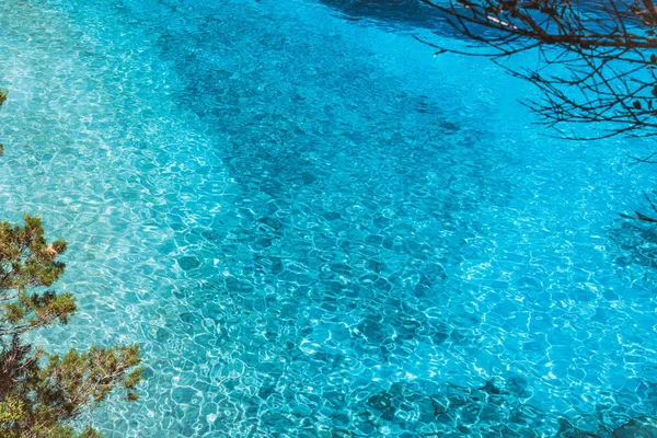 Blauer Wasserhintergrund. türkisfarbenes plätscherndes Wasser mit Sonnenreflexen — Stockfoto