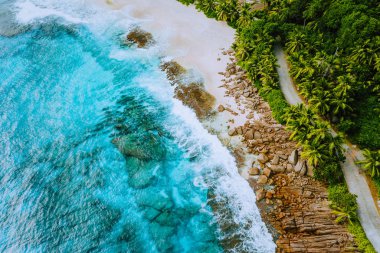 Seyşeller Mahe Island hava dron manzara sahil şeridi paradise sandy Beach palmiye ağaçları ve güzel masmavi okyanus dalgalarının Granit kayalar karşı haddeleme ile. Rüya gibi sığ lagün