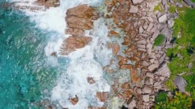 La Digue Adası, Seyşeller üzerinde kıyı şeridi granit kayalar sıçrayan dalgaları 4k hava kuş göz Görünümü görüntüleri