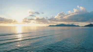 Ufukta tropikal ada silueti ile sakin deniz üzerinde Sunset 4k görüntüleri. Okyanus suyu üzerinde düşük irtifada Drone Uçan