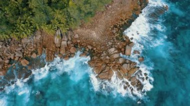 Anse Bazarca plajı yakınında granit kayalar üzerinde havai hava drone 4k uçuş. Okyanus dalgaları kayalara giriyor. Mahe adası, Seyşeller