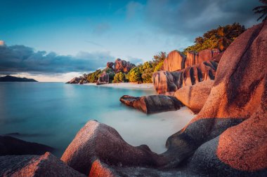 Unique shaped granite boulders and a dramatic sunset at Anse Source dArgent beach, La Digue island, Seychelles. Long Exposure clipart